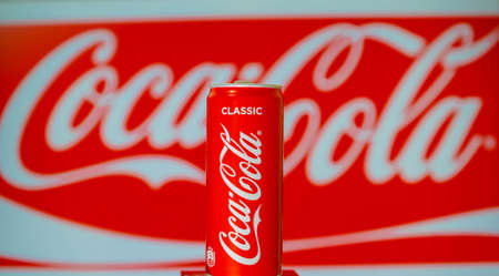 Aluminum can of soft carbonated beverage Coca-Cola against the background of advertising poster of brand Coca-Cola.のeditorial素材