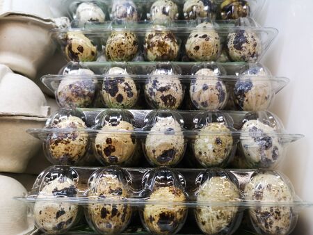 many quail eggs are for sale in egg trays on a grocery store shelf
