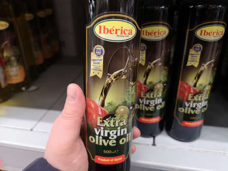 Glass bottle of natural olive oil Iberica Extra Virgin in hand against the background of a counter in a retail grocery store on May 5, 2020 in Russia, Tatarstan, Kazan, Richard Zorge Street 11bのeditorial素材