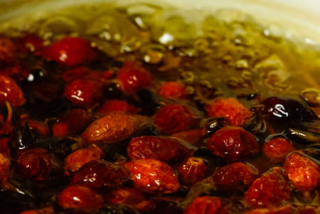close-up of rose hips are brewed in a saucepan on a gas stove.