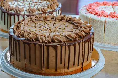 delicious sweet chocolate cake with butter cream on a table in a roadside cafe near other cakes.
