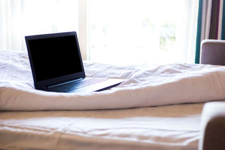 Bright hotel room in bed with a laptop in the morningの写真素材