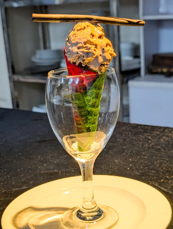 Creative dessert presentation featuring a vibrant green ice cream cone placed in a clear glass on a...