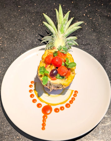 An innovative and tropical dessert or appetizer featuring a vibrant fruit saladâincluding cherry tomatoes, grapes, and pineapple chunksâpresented inside shell, complete with its leafy crown.の写真素材