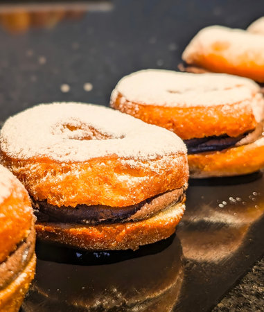A golden donut filled with rich chocolate cream and dusted with fine powdered sugar, placed on a...