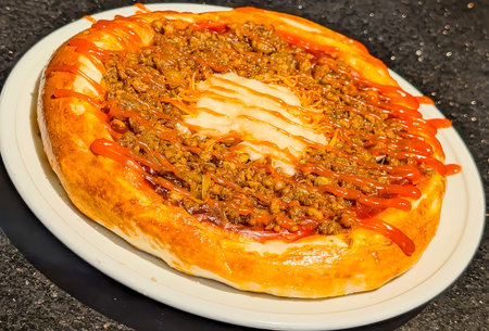A hearty and unique savory baked flatbread, topped generously with spiced ground meat, caramelized...