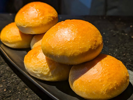 A visually striking stack of freshly baked, glossy brioche or milk buns, showcasing a rich...