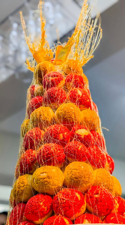 A spectacular, towering croquembouche dessert is dramatically constructed from stacked yellow and red choux pastry puffs, bound together by spun caramel threads.の写真素材