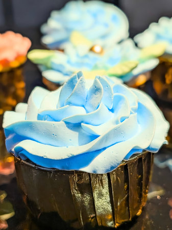 Vibrant close-up of a beautifully decorated cupcake topped with smooth blue buttercream swirled into an elegant rose shape.の写真素材