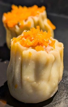 A close-up arrangement of traditional Chinese Siu Mai (Shumai) dumplings, beautifully steamed and garnished with vibrant shredded carrot topping.の写真素材