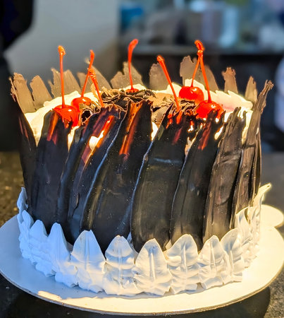 A high-angle, close-up view of a decadent Black Forest cake, decorated whipped cream frosting, large dark chocolate shards around the border, and a center mound of chocolate shavings.の写真素材