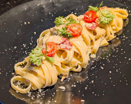 A close-up of Italian fettuccine pasta generously coated in a rich, creamy white sauce, mixed with succulent shrimp and sliced pink sausage.の写真素材