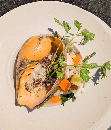 A gourmet seafood presentation featuring baler shell meat served with cooked carrots, green beans,...