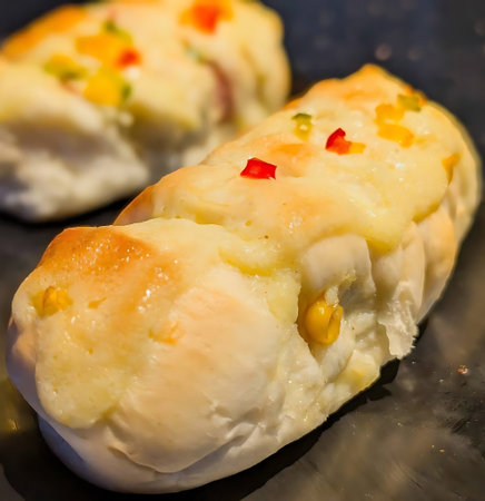 A golden stuffed bread roll topped with red and yellow peppers and cheese, surrounded by assorted...