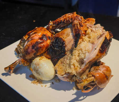 Crispy roasted chicken split open to reveal a savory rice stuffing, served with a boiled egg on a...