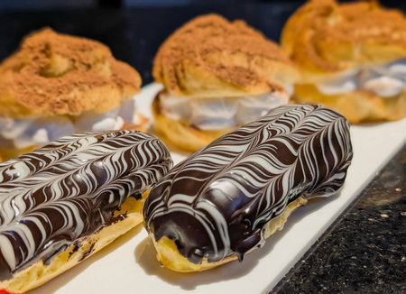 Gourmet chocolate eclairs with glossy glaze and white icing swirls, paired with cocoa-dusted cream...