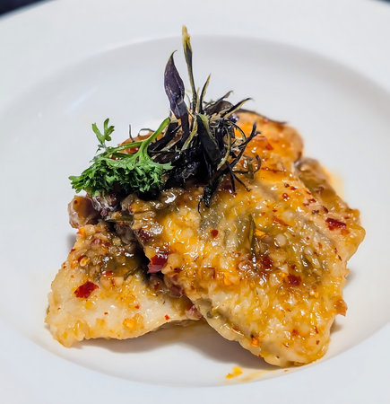 Crispy fish fillets coated in a rich orange chili glaze, garnished with parsley and shredded...