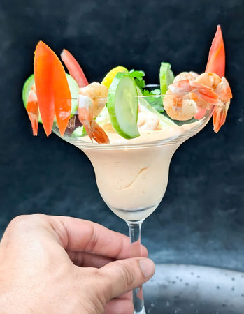 Shrimp cocktail with plump shrimp and creamy orange sauce served in a margarita glass, garnished...