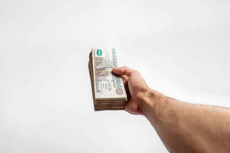 Man arm Holding bundles of Egyptian money currency 100 pound on isolated White Backgroundの写真素材