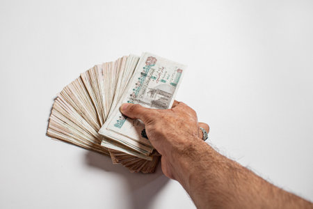 Man arm Holding bundles of Egyptian money currency 100 pound on isolated White Background