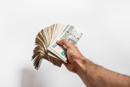 Man arm Holding bundles of Egyptian money currency 100 pound on isolated White Backgroundの写真素材