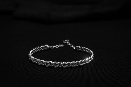 A silver chain bracelet with a twisted design, set against a black background.の写真素材