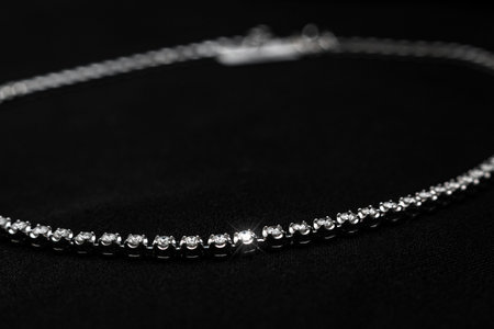 A luxury diamond necklace with a delicate chain and shimmering stones, set against a black...