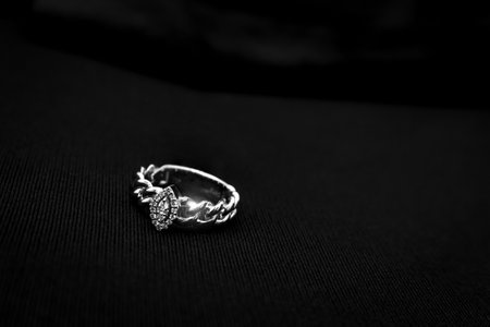 A delicate white gold diamond ring featuring a floral motif design, placed elegantly on a black...