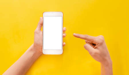 hand holding a mobile phone on yellow background social media, e-commerce, website, bannerの写真素材