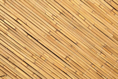 Wall detail made of thatch. Yellow reed wall decor. Thin bamboos arranged diagonally.
