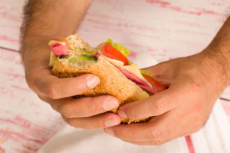 close-up man holding a sandwich with small biteの写真素材