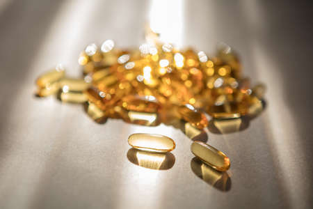 Vitamins pills of yellow color isolated on white background. Cod liver oil. Fish oil capsule pills closeup backgroundの写真素材