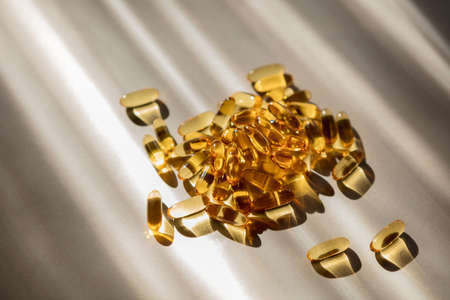 Vitamins pills of yellow color isolated on white background. Cod liver oil. Fish oil capsule pills closeup backgroundの写真素材