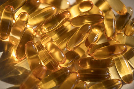 Vitamins pills of yellow color isolated on white background. Cod liver oil. Fish oil capsule pills...