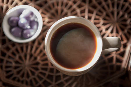 A cup of instant coffee place on old wood background with Shiny milk chocolate coated round chocolate ballsの写真素材