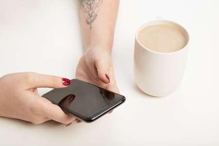 Woman text messaging on a mobile phone in a close up view of her hands and the blank screen...