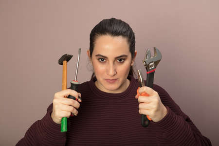 Capable young woman holding a set of tools in her hands in a concept of DIY, repairs and renovationsの写真素材