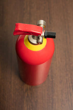 Top down view on a portable red fire extinguisher on a wood floor with focus to the nozzleの写真素材