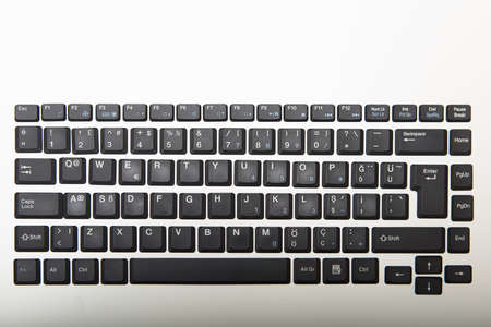 Overhead view of a Qwerty alphanumeric computer keyboard with black keys on silver gradient to white...