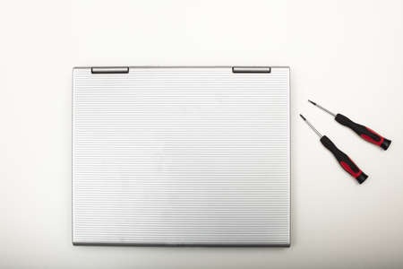 Modern laptop computer with precision tools lying on a white background viewed from above in a maintenance and DIY repair conceptの写真素材