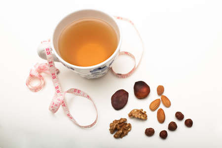 Assorted dried healthy nuts with black tea and a tape measure in a concept of weight loss through correct diet and nutritionの写真素材