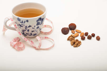 Assorted dried healthy nuts with black tea and a tape measure in a concept of weight loss through correct diet and nutritionの写真素材