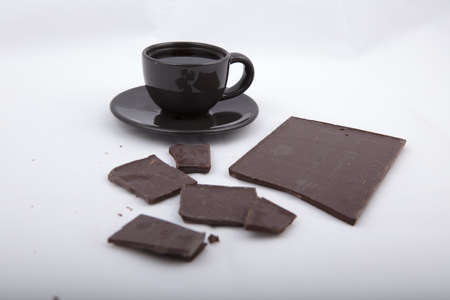 Black cup of coffee on a saucer with chocolate over gray background with copy spaceの写真素材