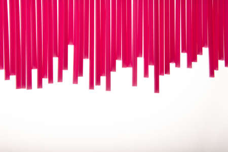 Red straws in a decorative background pattern two-thirds into the frame in an uneven line over a white background with copy spaceの写真素材