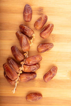Branch of dried  dates  on a wooden background, fruits of date palm with text area , top view, high...