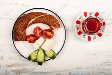 Turkish breakfast with simit, cheese, cherry tomato, cucumber, and tea isolated on wooden table top...