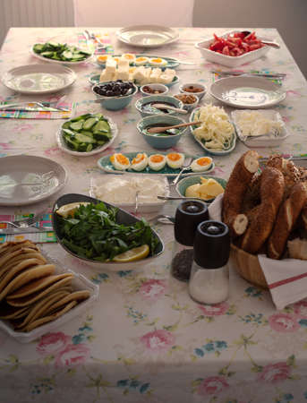 Turkish breakfast with simit(bagel), pancake, cheese, cherry tomato, cucumber, and tea on a table...