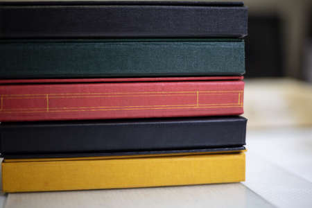 Spines of stacked books in assorted colors and textures with bespoke binding at a book binder in a close up viewの写真素材