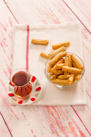 Crunchy grissini with Turkish tea ready to serve on cloth napkin top view on wooden table