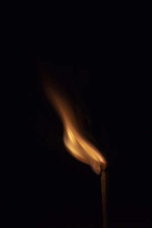Match with strongly flaring flame on a black background closeup